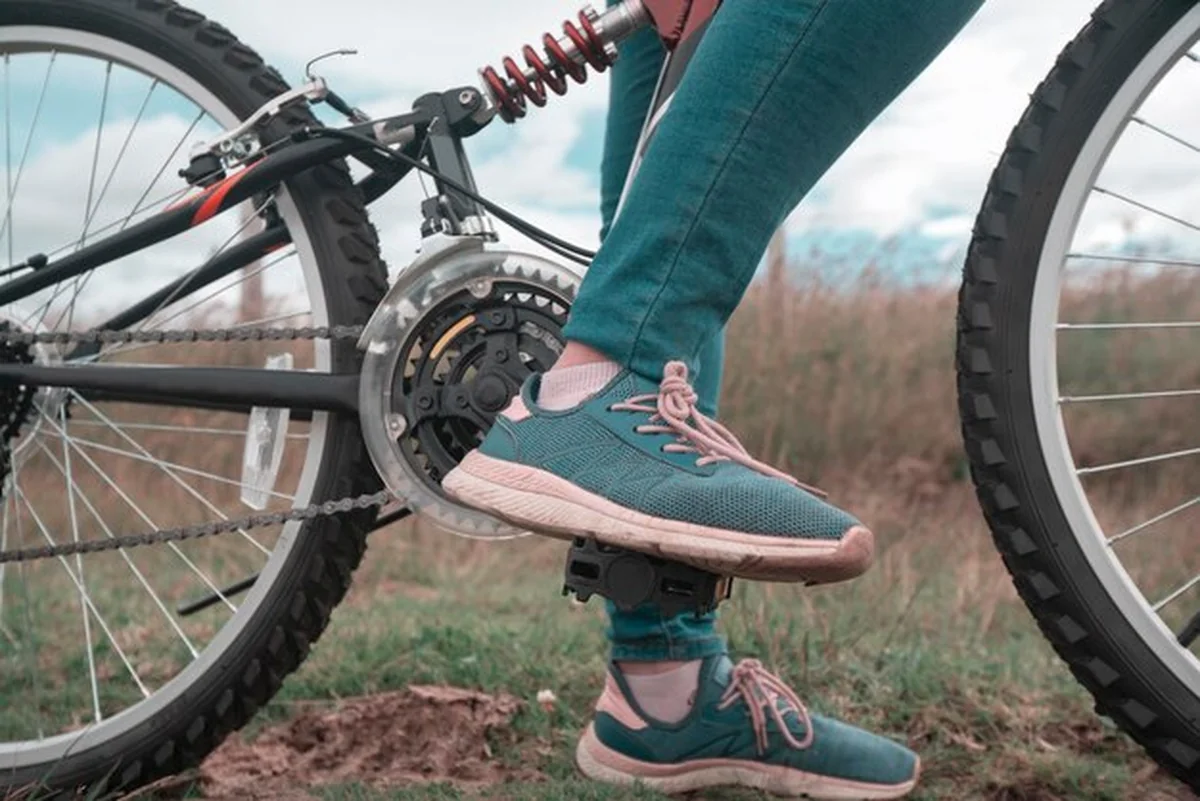 Stopy młodej kobiety w niebieskich spodniach na pedałach roweru