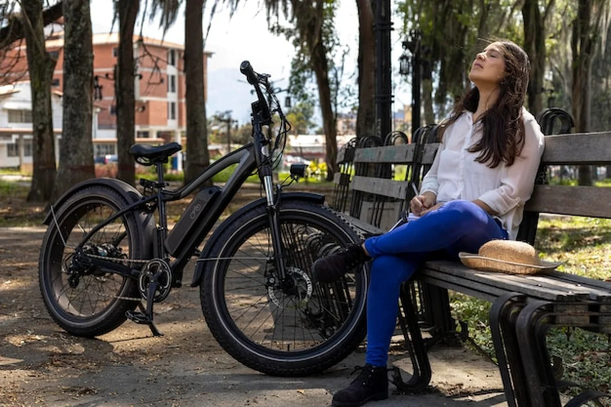 Młoda kobieta odpoczywa na ławce obok roweru elektrycznego