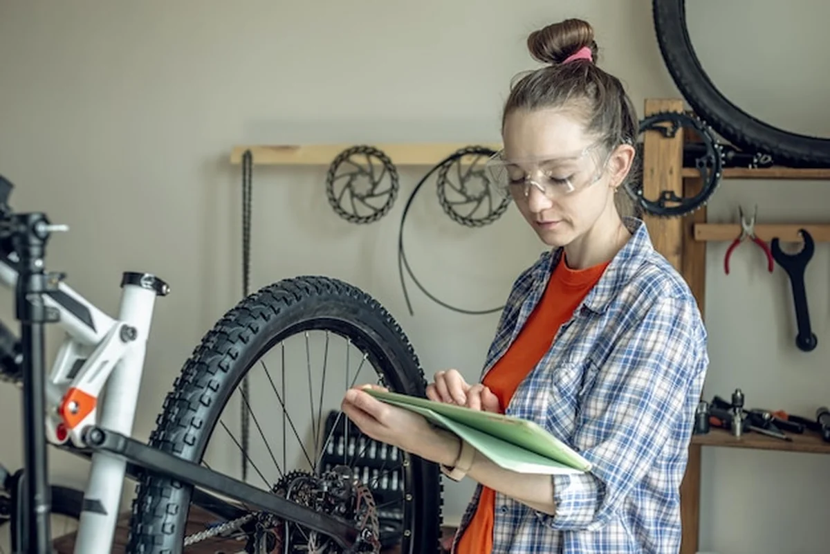 Kobieta naprawia górski rower w warsztacie rowerowym
