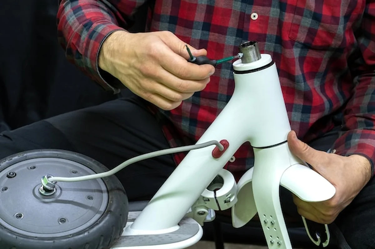 Mistrz naprawia skutery elektryczne, trzyma złamaną część i koło silnikowe, wymienia dętkę i oponę