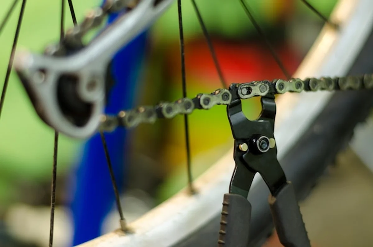 Mechanik w warsztacie trzyma narzędzie do wymiany łańcucha rowerowego