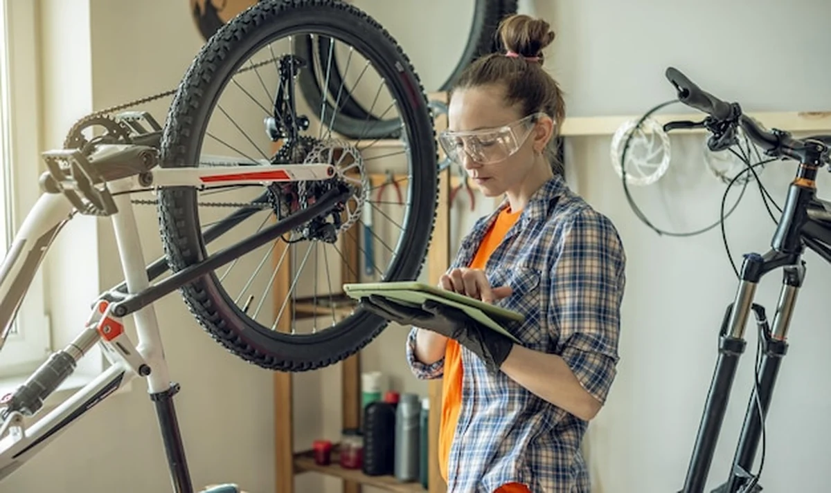 Kobieta naprawiająca rower w warsztacie. Koncept przygotowań do sezonu, naprawy i konserwacji