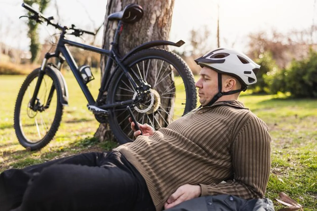 Mężczyzna sprawdzający smartfon na łące w parku miejskim