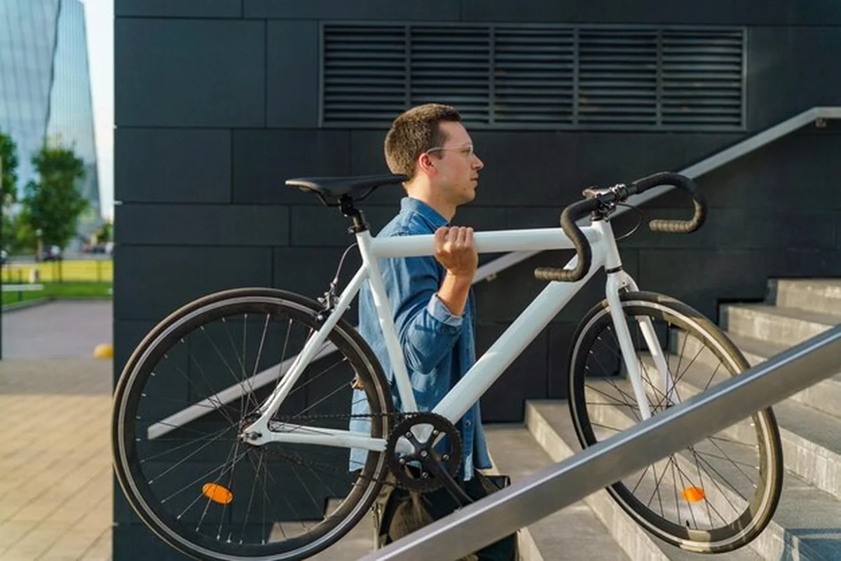 Młody mężczyzna niosący rower po schodach w środowisku miejskim