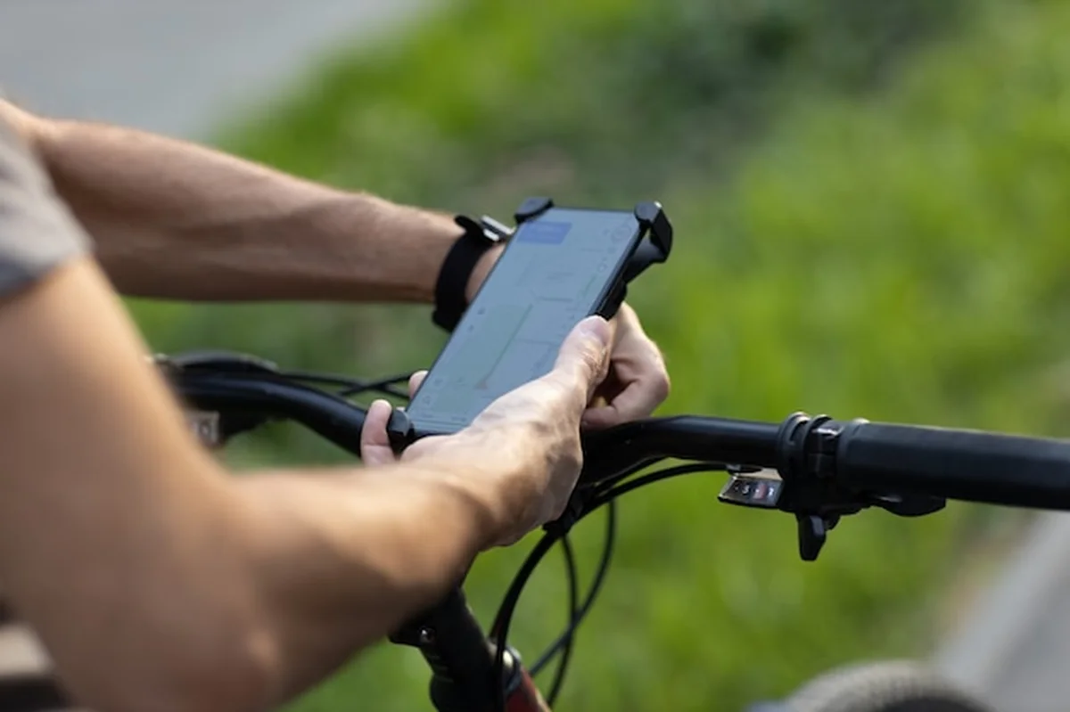 Człowiek planuje trasę rowerową za pomocą aplikacji GPS na smartfonie obok roweru. Podłączanie urządzenia