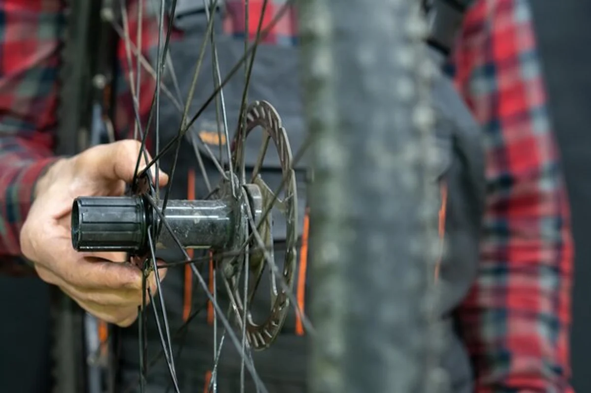 Mechanik trzyma koło w dłoni w warsztacie rowerowym