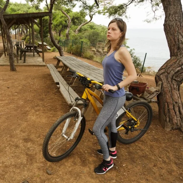 Kobieta rowerzysta z rowerem w parku publicznym