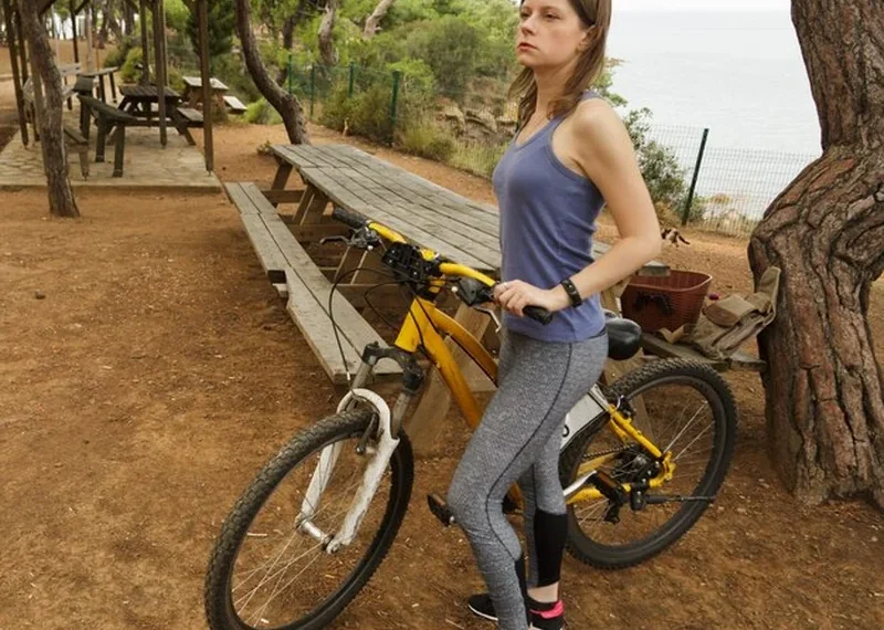 Kobieta rowerzysta z rowerem w parku publicznym