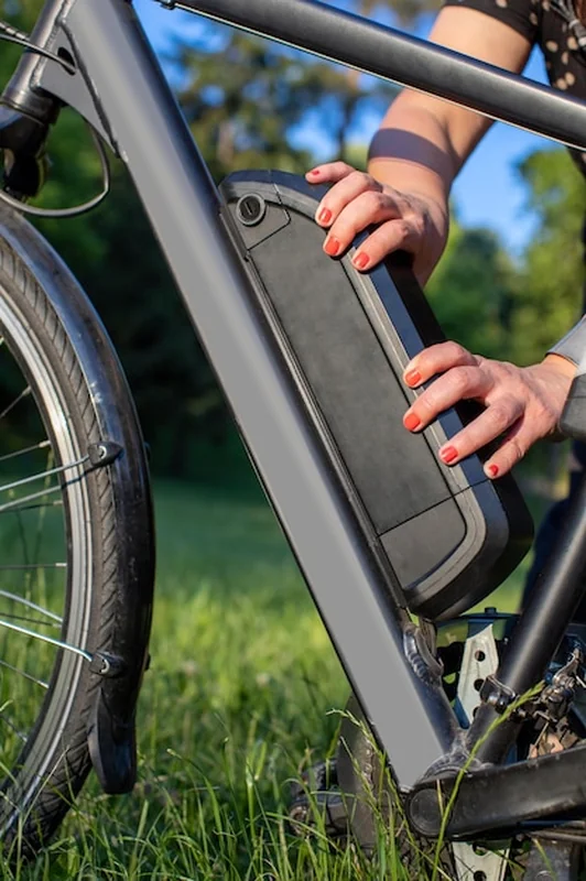 Kobieta trzymająca akumulator roweru elektrycznego na ramie