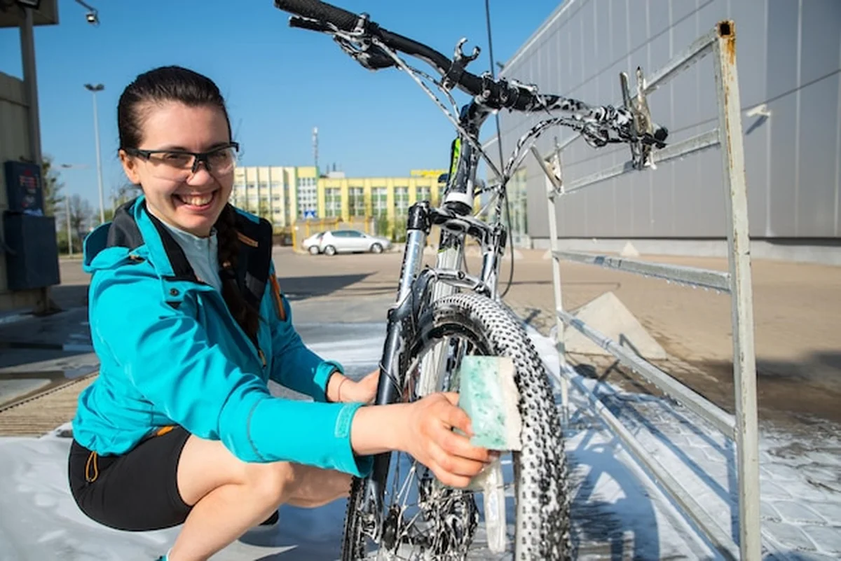 Młoda sportowa kobieta myjąca rower w samoobsługowej myjni samochodowej